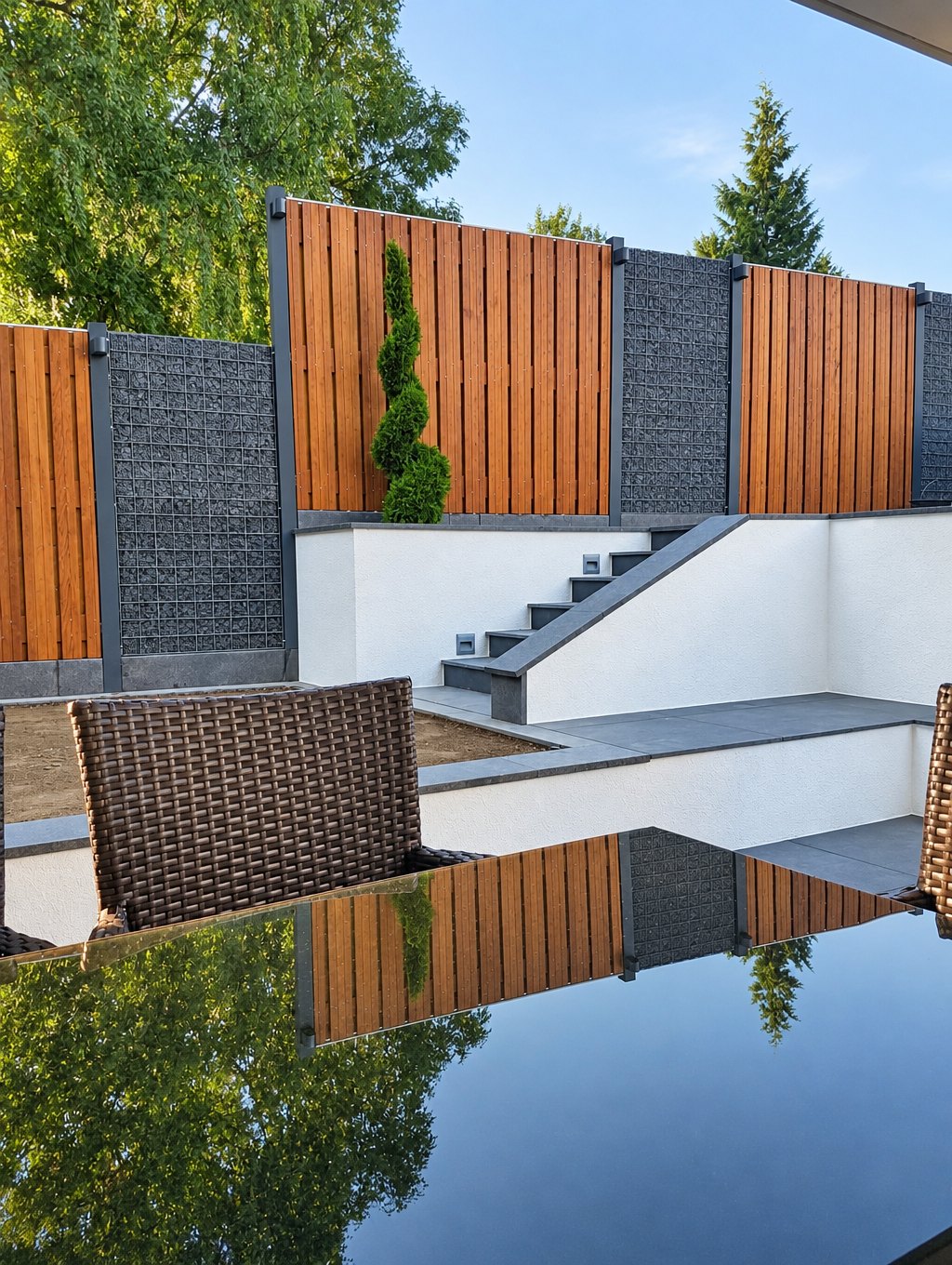 Terrasse mit anthrazitfarbenen Keramikplatten, weißen Mauern und Treppe